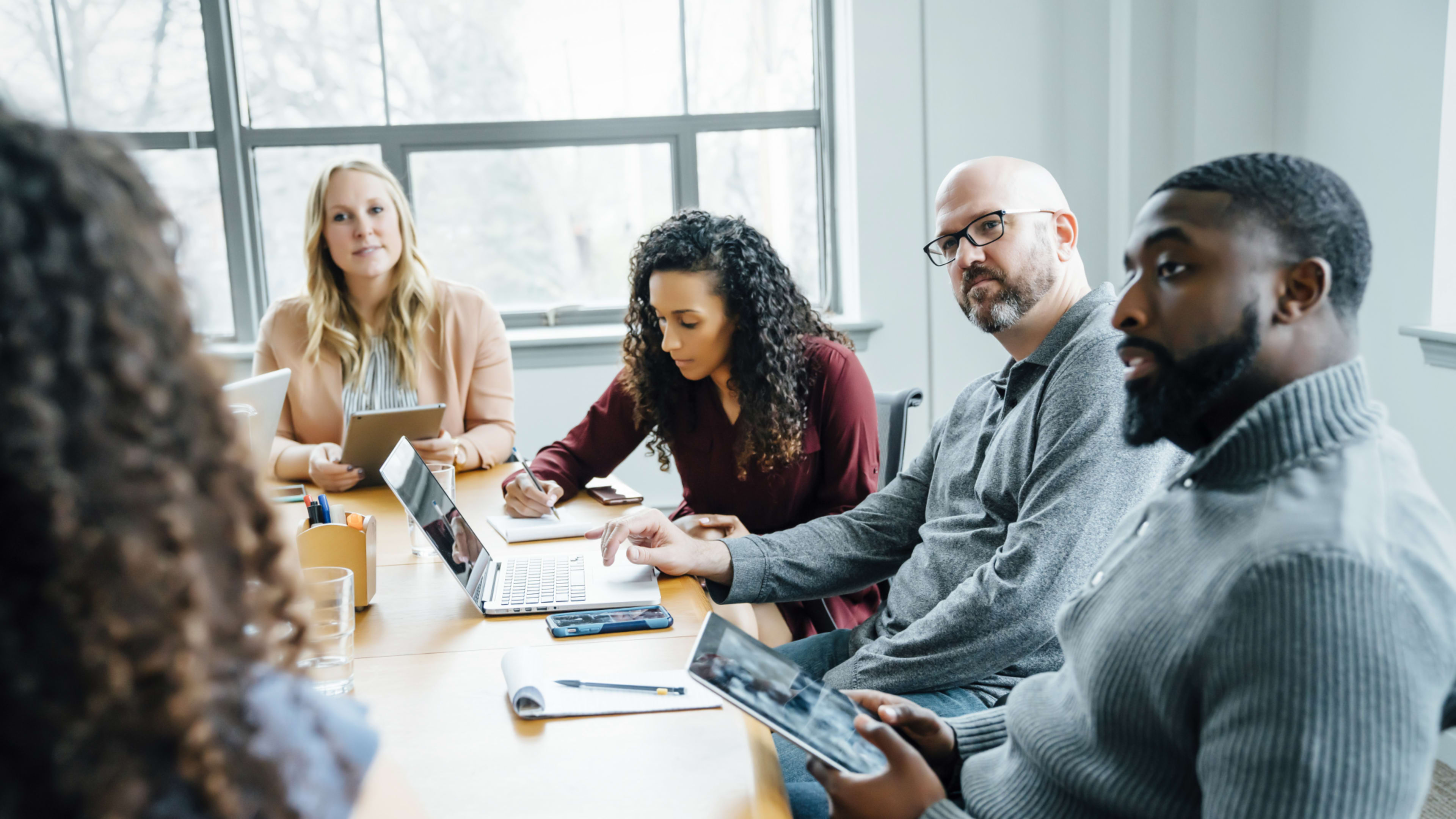 A group of five people interacting during a boardroom meeting.